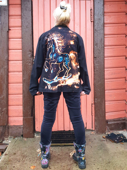 Back view of the “Cosmic Skatehorse” hand-painted black cotton jacket featuring a horse on a skateboard painted in white and blue.