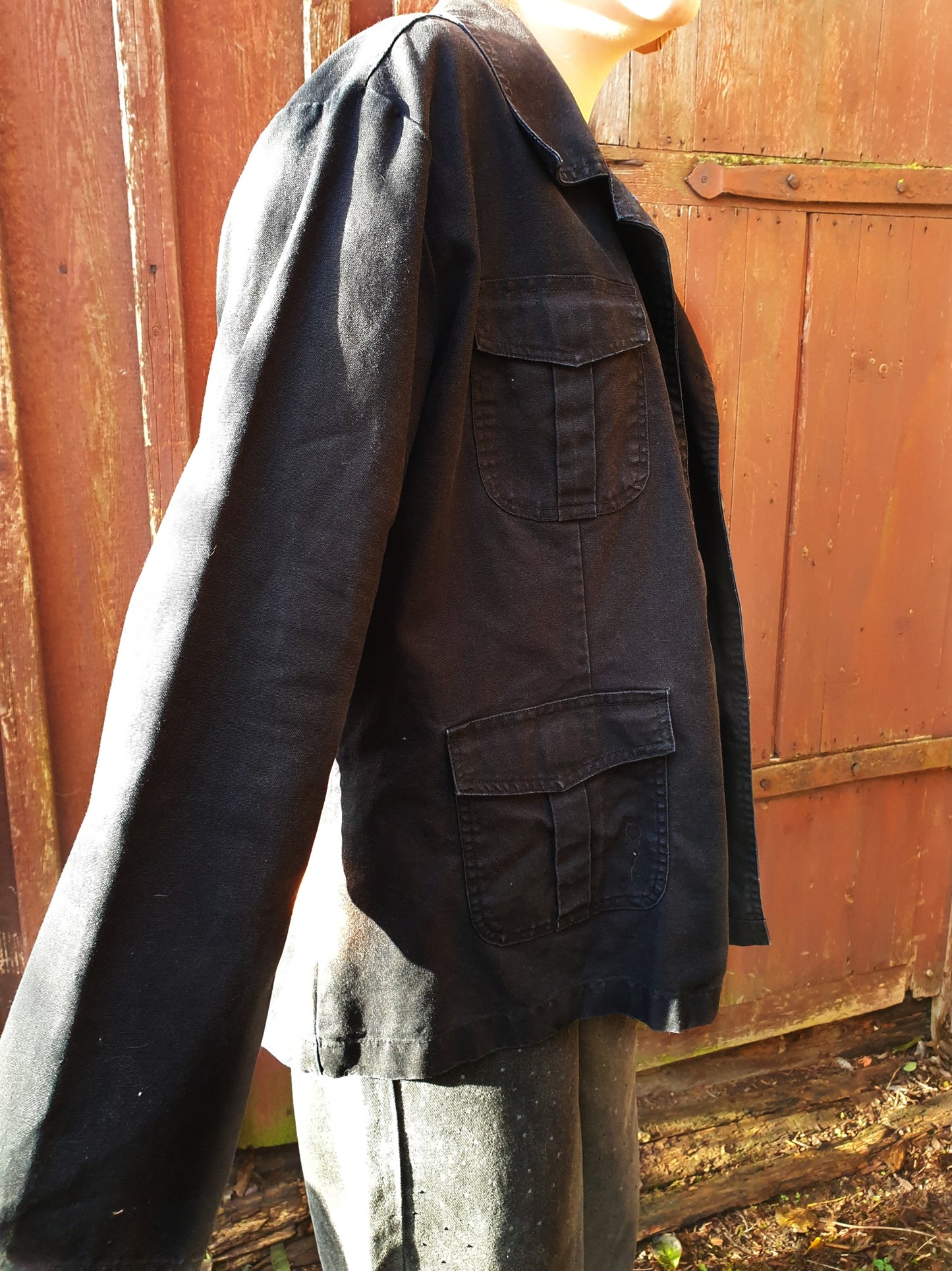 Side view of the black cotton jacket showing its boxy fit and mid-weight texture.