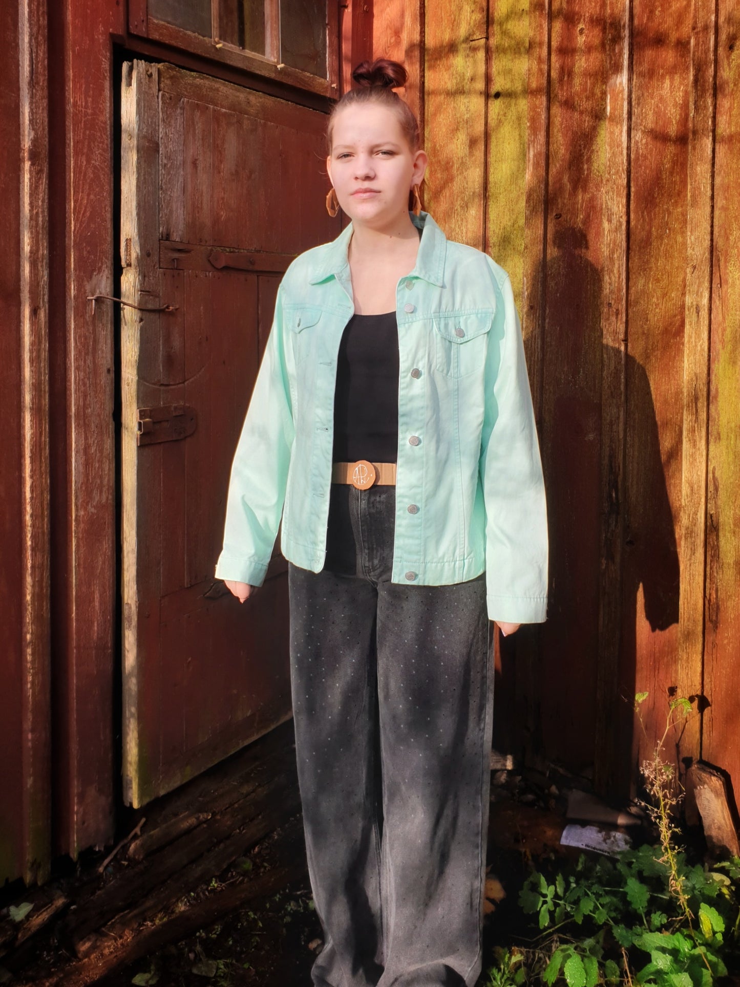 Front view of the light green upcycled denim jacket with two pockets and button closure.