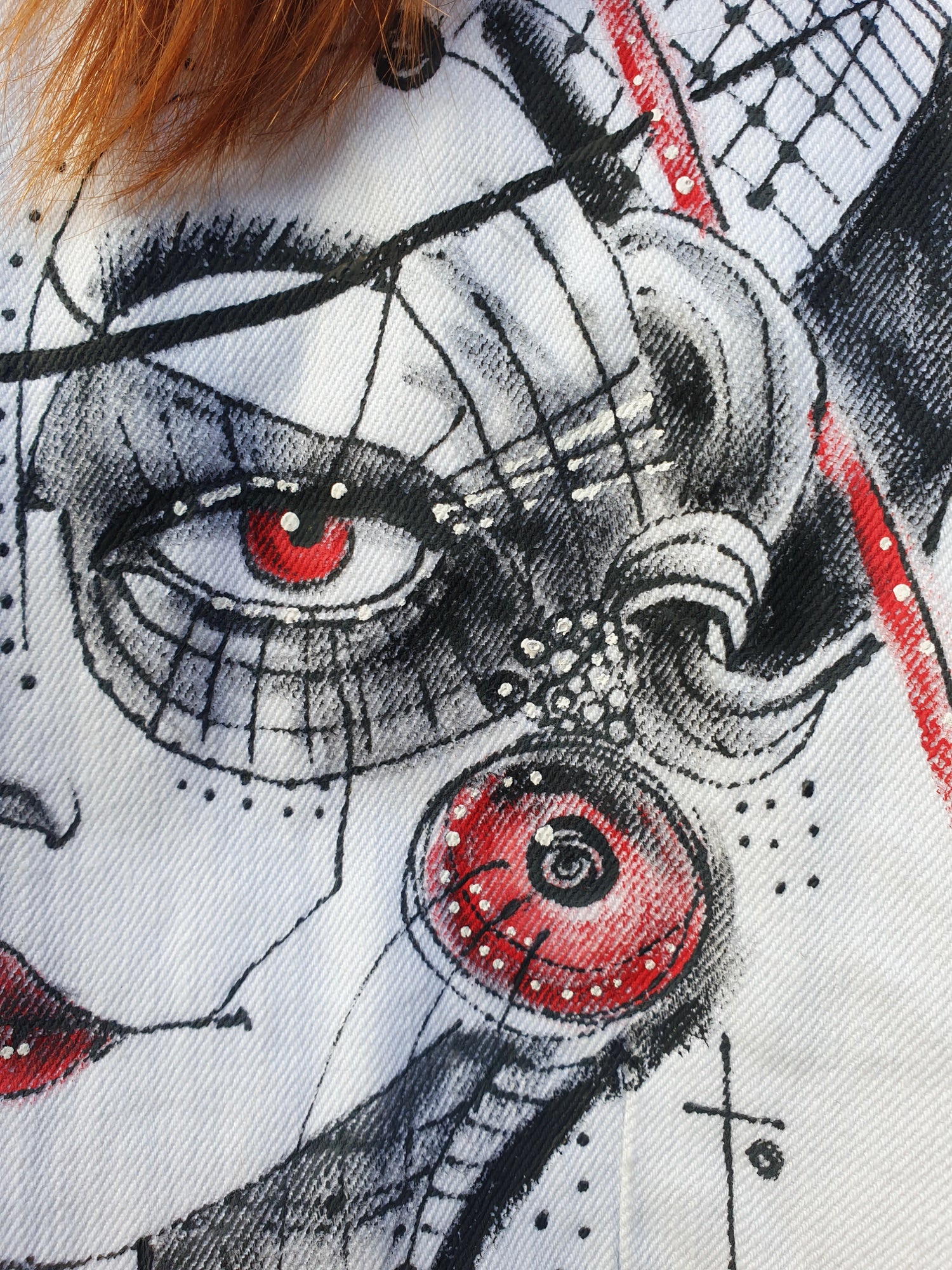 Close-up of the painted portrait in red and black tones with geometric details.