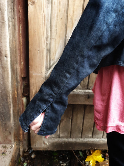 Close-up of the sleeve slit detail on the hand-painted denim jacket.