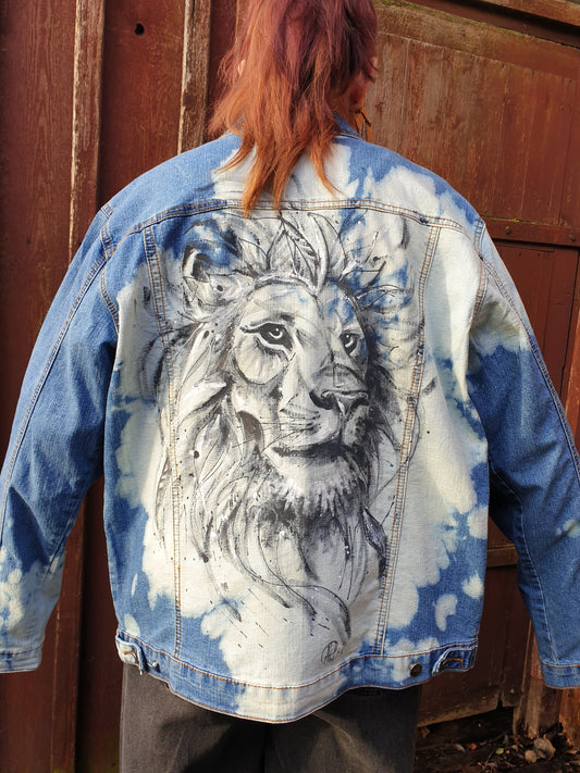 Back view of the jacket showing a detailed hand-painted lion on a cloudy bleached denim background.