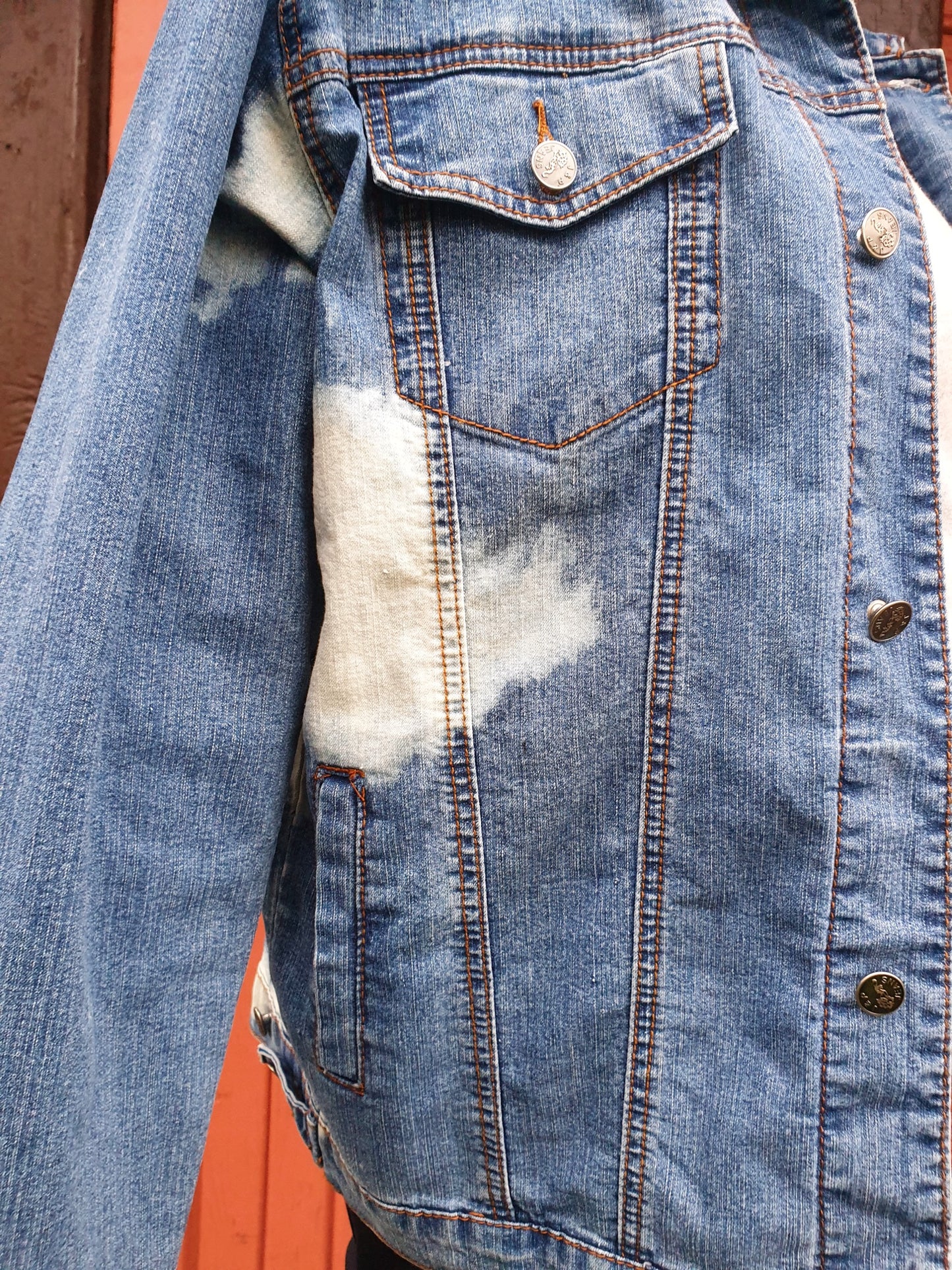 Detail of front pocket and stitching on the upcycled denim jacket.