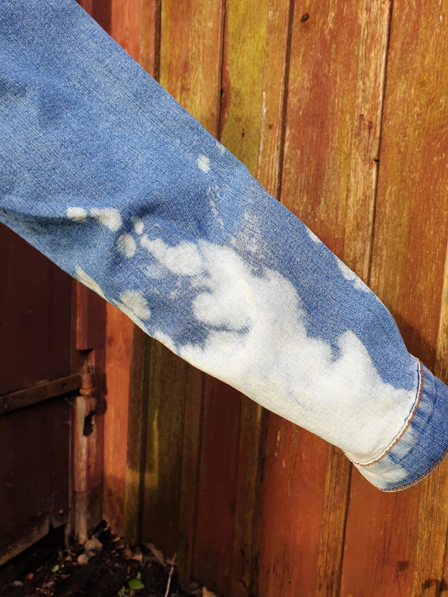 Close-up of the sleeve with soft white bleach clouds on light blue denim.
