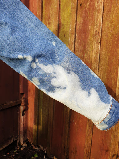 Close-up of the sleeve with soft white bleach clouds on light blue denim.