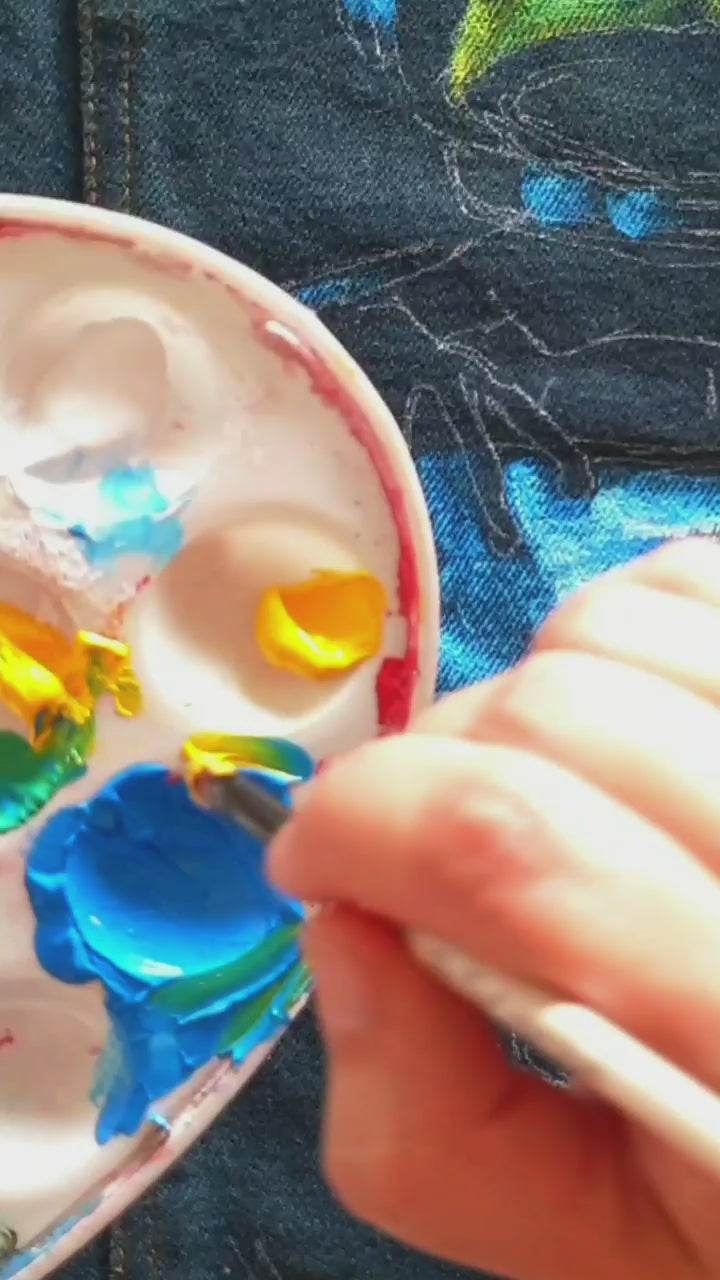 Painting process of the Space Frog Commander hand-painted upcycled denim jacket by Hele Artwear, capturing the creation of the cosmic frog artwork.