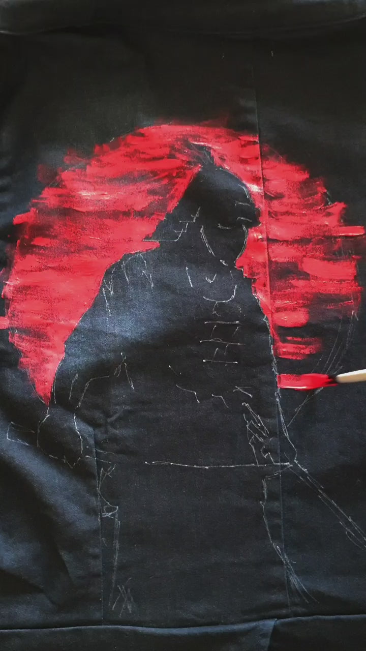 Painting  the “Sunset Samurai” hand-painted deep navy denim jacket showing a samurai silhouette against a red sunset.
